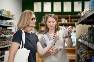Two women examining food items on display in a grocery store aisle